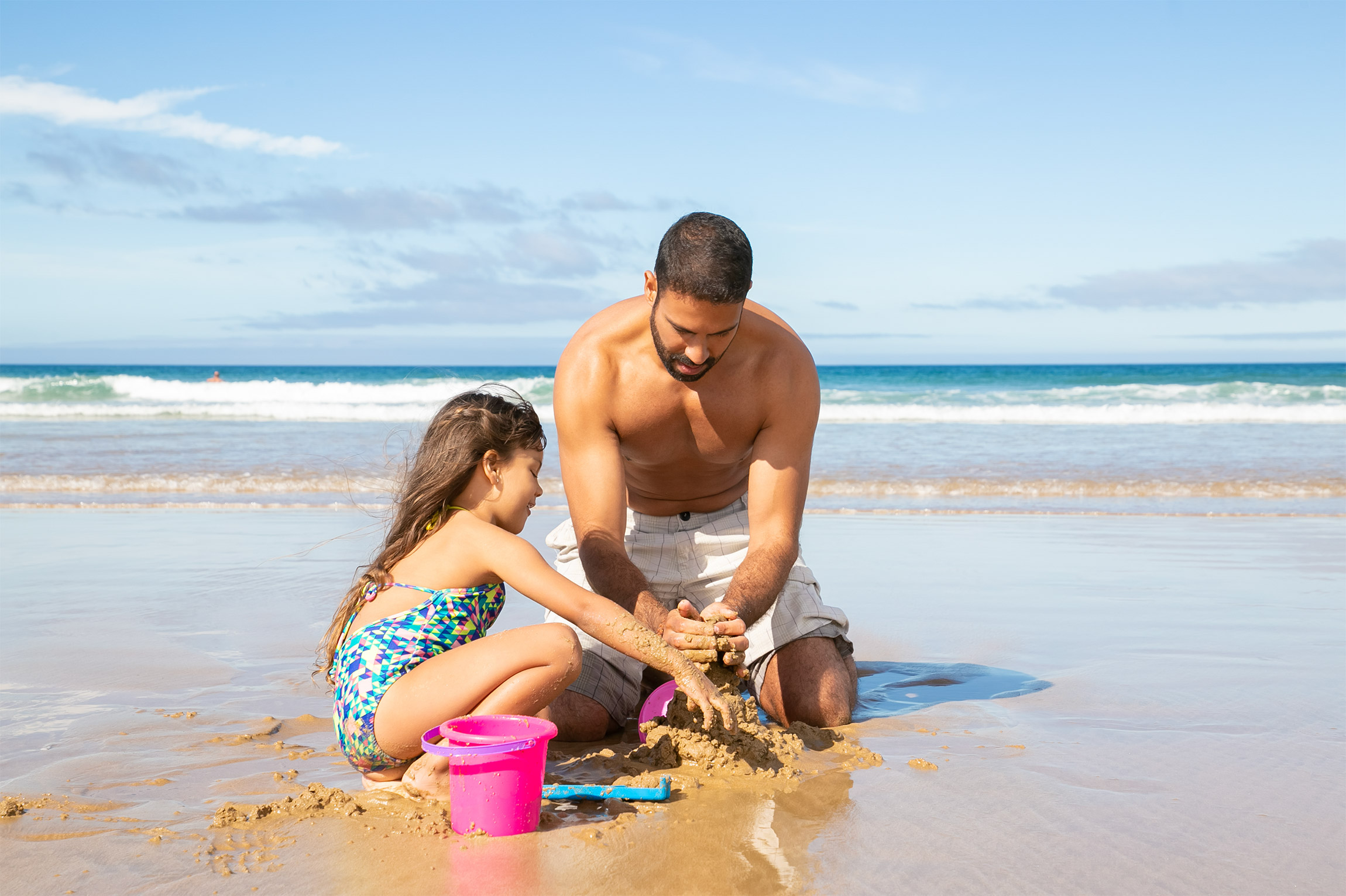 adorable little girl her dad building sandcastle beach sitting wet sand enjoying vacation.