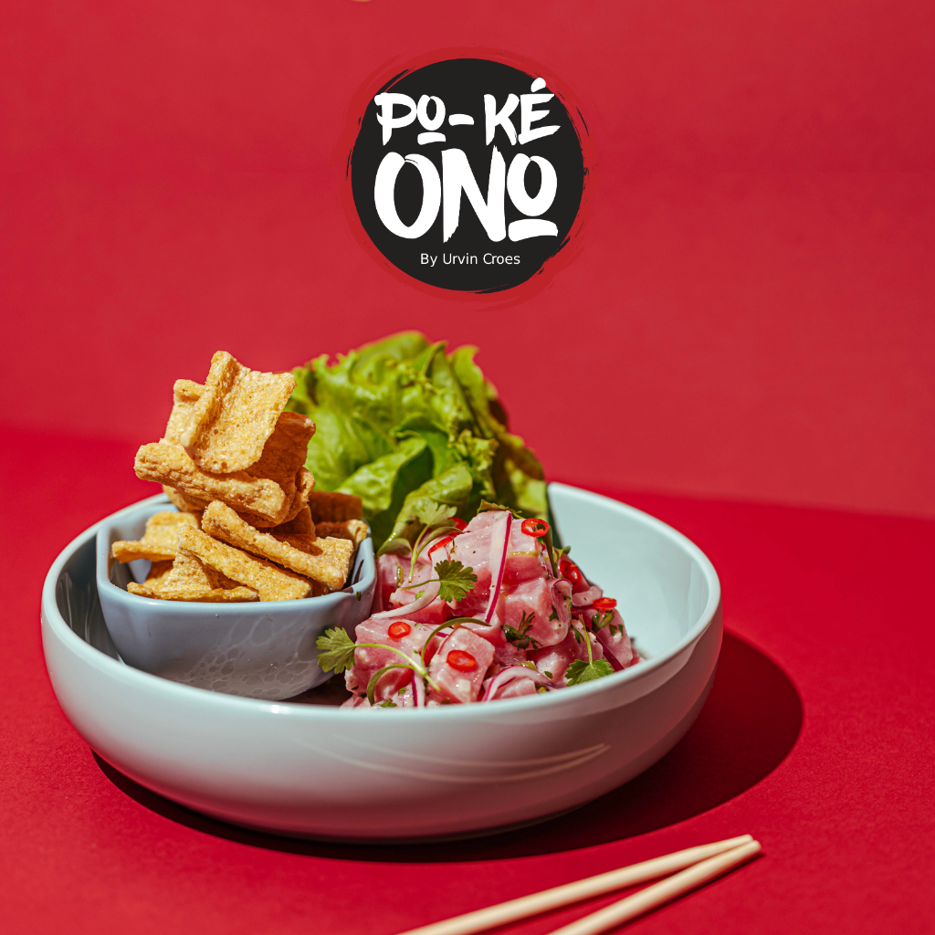 Vibrant poke bowl featuring fresh tuna, lettuce, crispy crackers, and red chili peppers served at Po-Ké Ono by Urvin Croes on a red background.